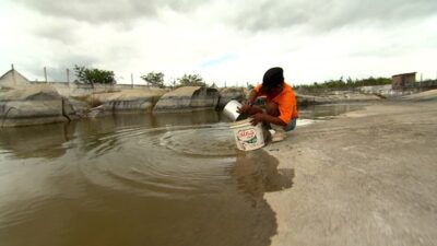 Homem pegando água suja para beber (Foto: Divulgação / Record)