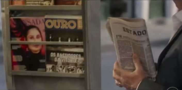 Personagem lê exemplar do fictício jornal "Estado" na novela. (Foto: Reprodução/TV Globo)