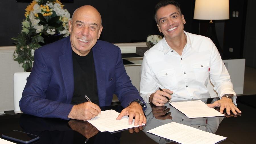 Leo Dias acerta contrato com a RedeTV!; na foto, o jornalista aparece com o presidente da emissora, Amilcare Dallevo Jr. Imagem: Divulgação/RedeTV!