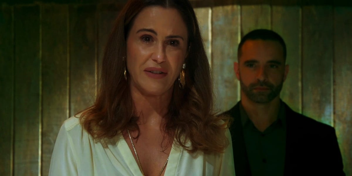 Dominique usa vestido branco, colar de ouro e está em cativeiro em cena da novela Salve-se Quem Puder