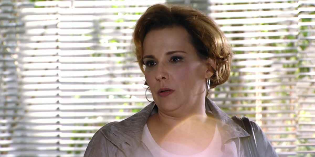 Eva usa casaco de manga longa, blusa branca e brincos de argola em cena da novela A Vida da Gente