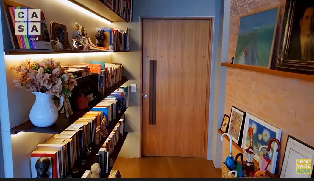 A entrada da casa da atriz Maria Clara Gueiros conta com muitos livros e quadros, apesar de ter muitas coisas, é tudo muito bem organizado (Foto Reprodução/Youtube) 