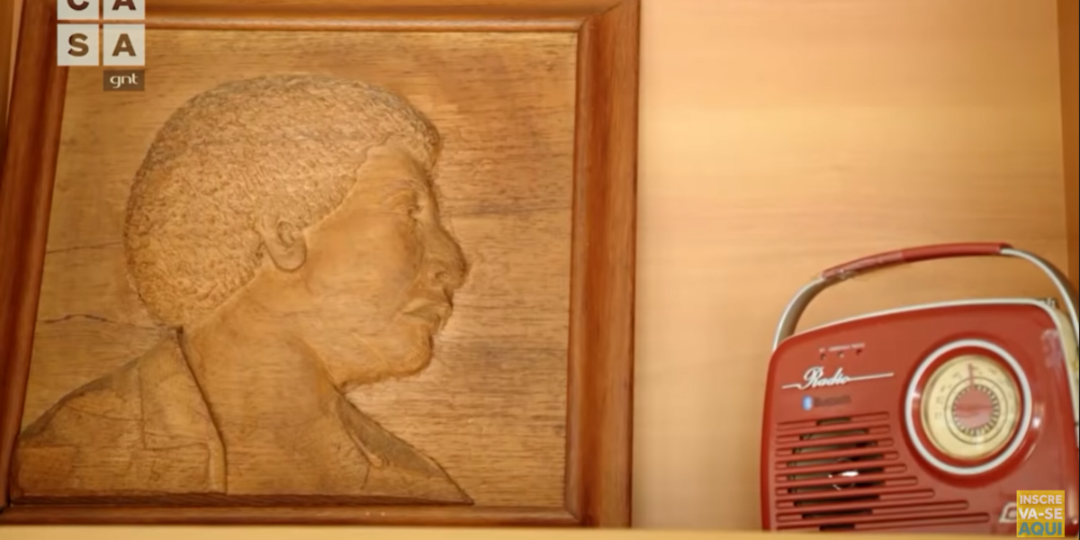 Quadro de madeira retratando o pai de Diogo Nogueira ao lado de um rádio antigo (Foto Reprodução/Youtube)