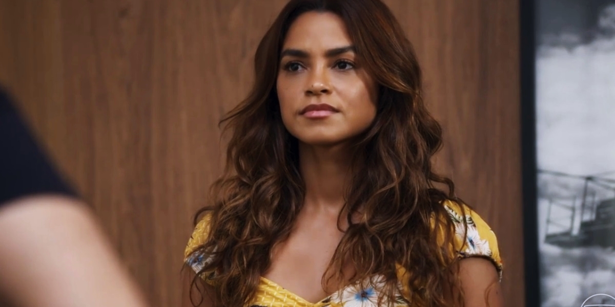 Brisa em cena da novela travessia usando vestido amarelo, com flores e cabelo longo cacheado