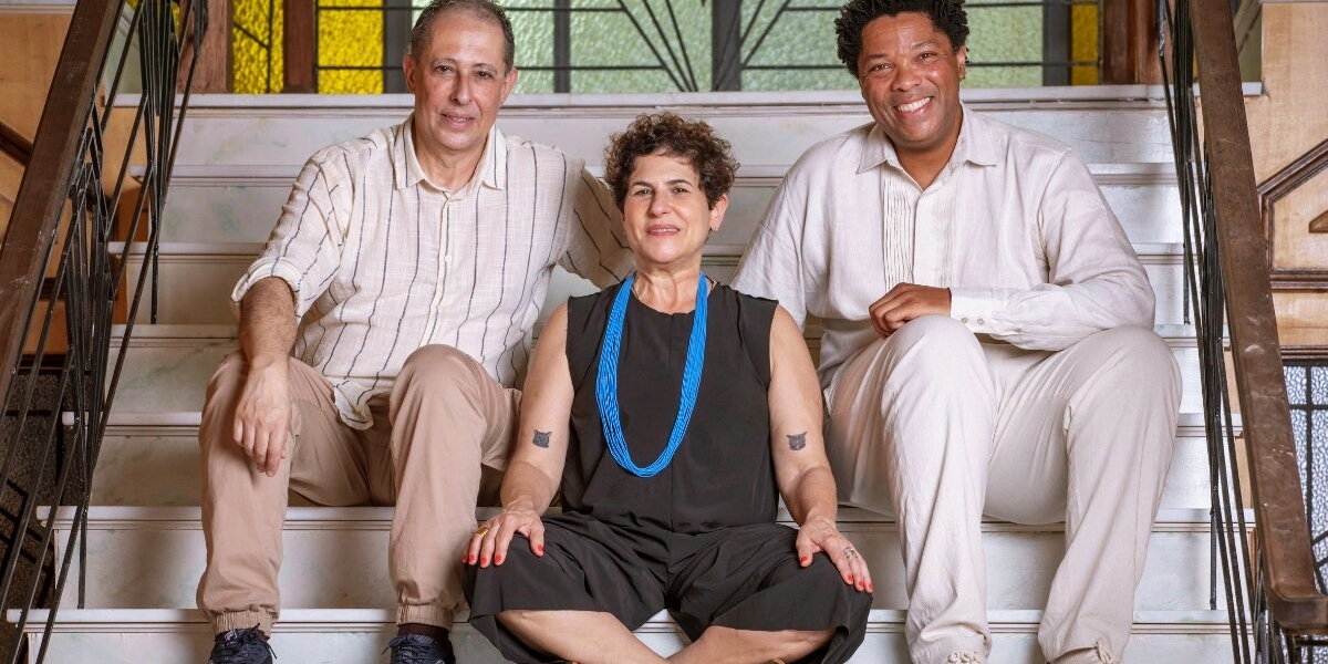 Duca Rachid, Júlio Fischer e Elísio Lopes Jr, autores de Amor Perfeito, sentados em uma escadaria