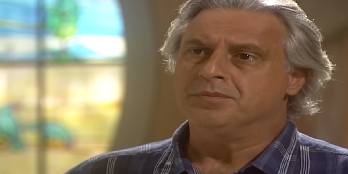 Bruno em cena da novela O Rei do Gado usando cabelo grisalho e camisa azul xadrez