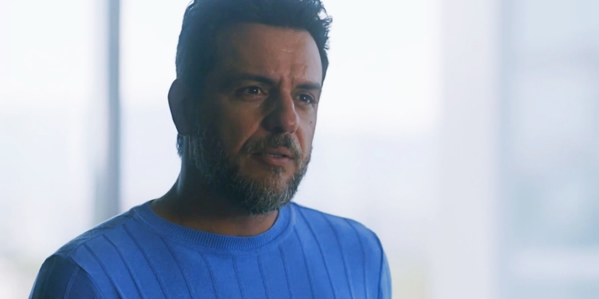 Moretti em cena da novela Travessia com expressão séria e camisa azul clara