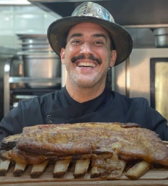 André Marques na cozinha com uma costela em mãos (Foto: Reprodução/ Internet)