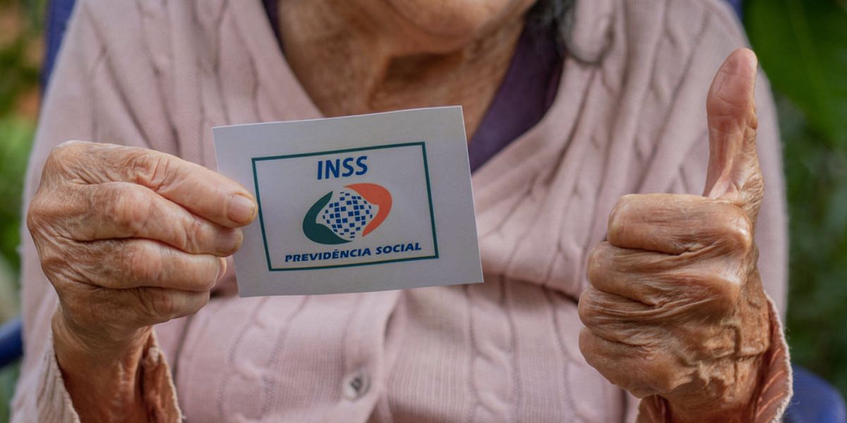Idosa segurando cartão do INSS (Foto: Reprodução / Internet)