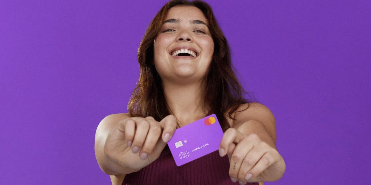 Pessoa feliz segurando cartão do Nubank (Foto: Reprodução / site do banco)