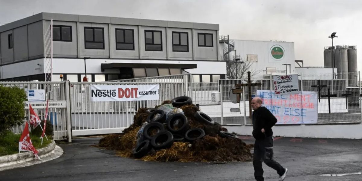 Pedestre passa diante da fábrica das pizzas Buitoni em que funcionários queimaram pneus como forma de protesto contra seu fechamento (Foto: Reprodução / François Lo Presti)