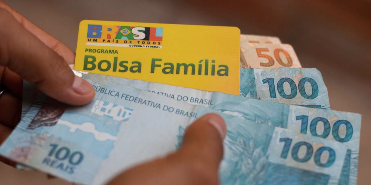 Beneficiário segurando notas de cem e cinquenta reais e cartão do Bolsa Família (Foto: Reprodução / Internet)