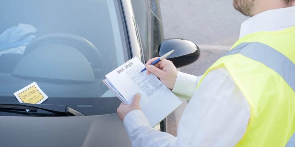 Homem aplicando multa em carro (Foto: Reprodução / Internet)