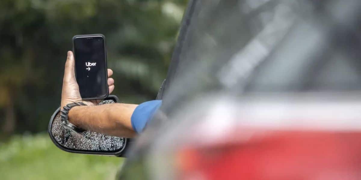 Motorista segurando aplicativo da Uber (Foto: Reprodução / Celso Tavares/G1)