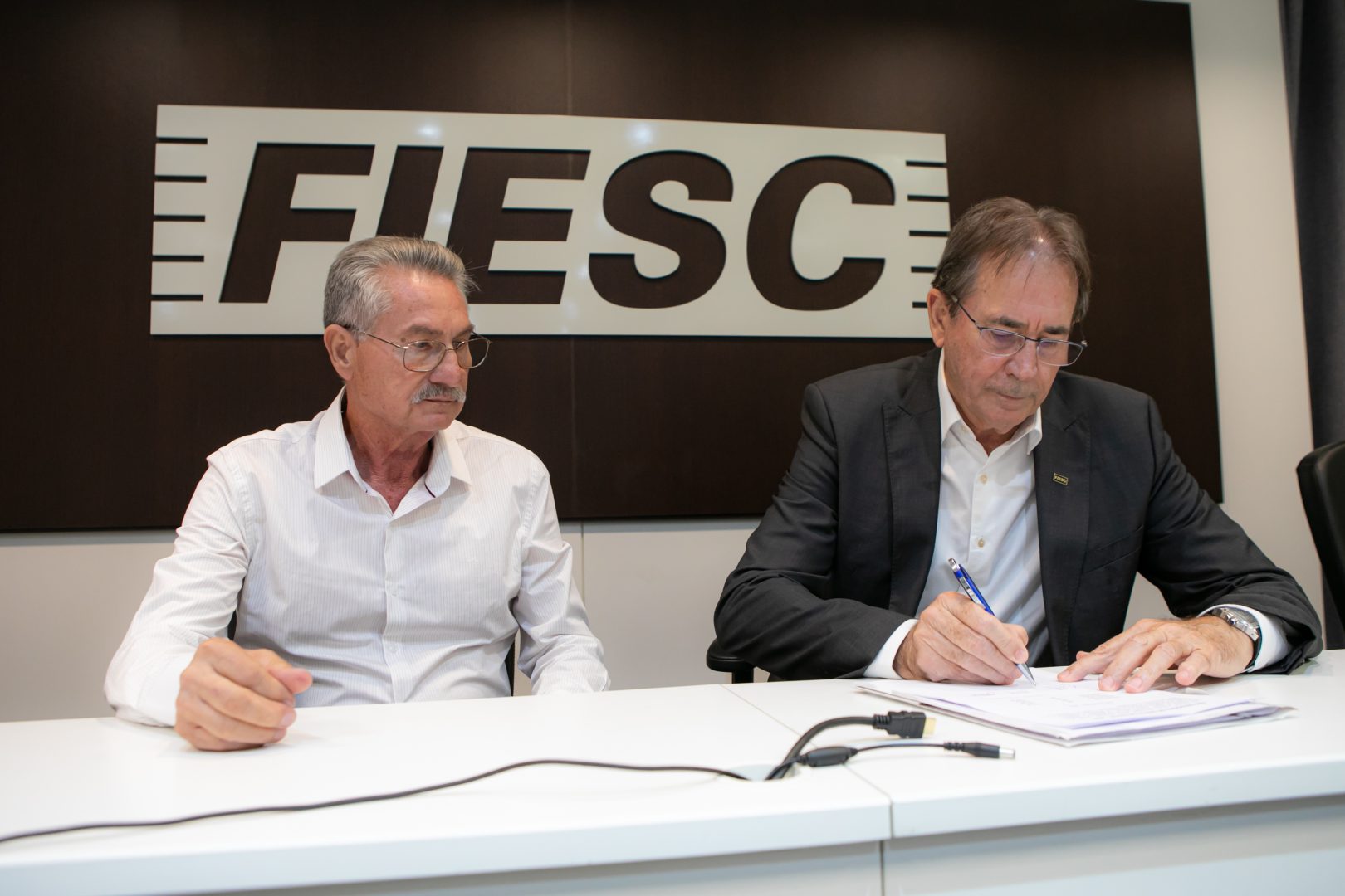 Ivo Castanheira (E), representante dos trabalhadores, e Mario Cezar de Aguiar (D), da Fiesc, em nome das empresas, selaram o acordo (Foto Reprodução/Filipe Scotti)