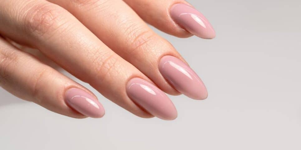 Mão com esmalte nude (Foto: Canva)