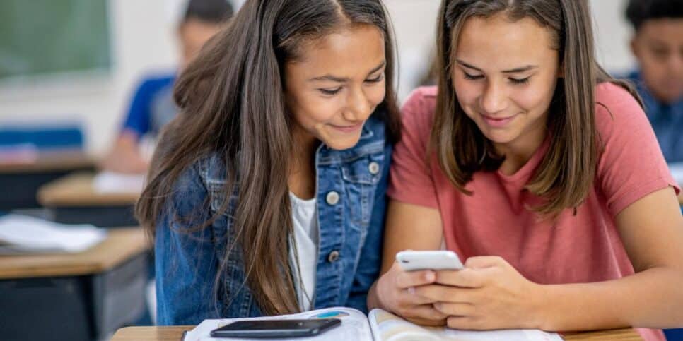 Ilustração alunas com celular na sala de aula (Foto: Canva) 